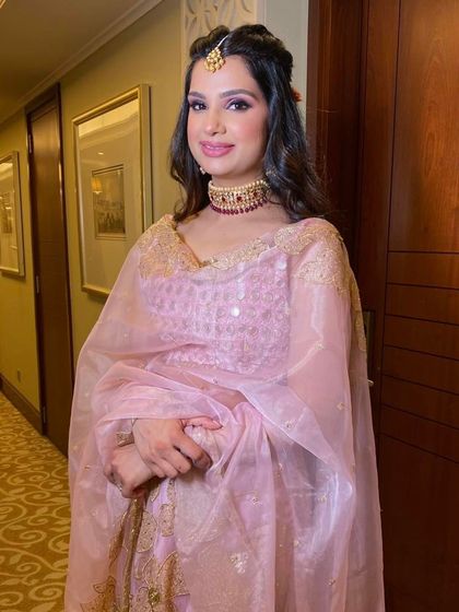 Another shot of this enchanting party look. The soft lighting in the hallway highlights her radiant skin and the delicate details of her pink outfit.