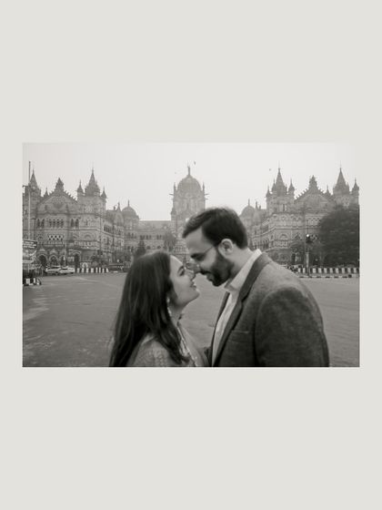 An intimate black and white portrait in front of the iconic CST station. The focus is entirely on their connection, with the grand monument as a soft backdrop.