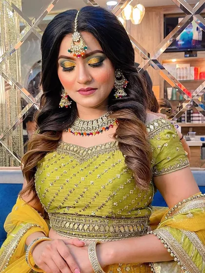 We love creating bold and vibrant looks for our clients. This photo showcases a stunning Haldi or Mehendi look, featuring a dramatic yellow and green smokey eye, contoured cheeks, and a hairstyle that complements the entire festive outfit.