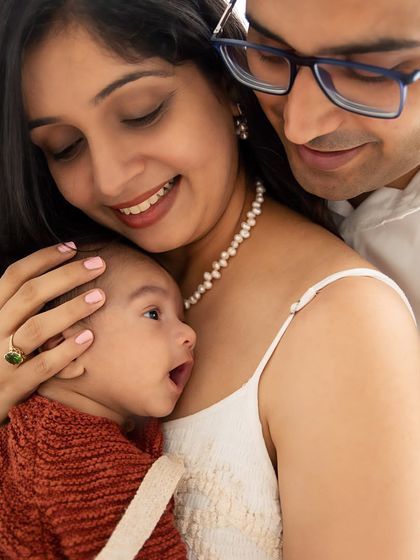 A close-up of the family's embrace, with the baby looking up in wonder. I focus on capturing the interaction and bond between family members.