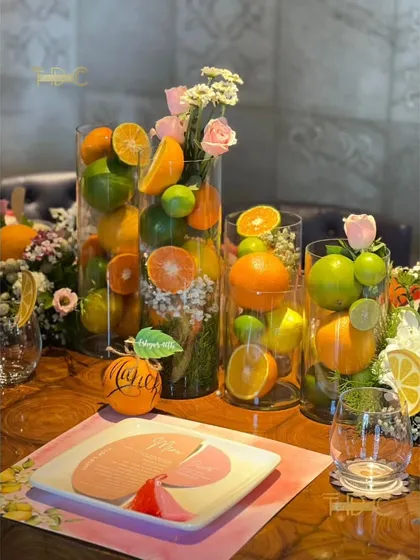 This summer birthday tablescape is bursting with freshness, using tall glass vases filled with whole lemons, limes, and oranges, interspersed with delicate floral bouquets.