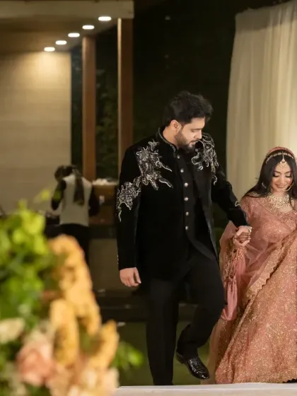 The groom gently guiding his bride into their reception. This candid shot captures a simple, loving gesture amidst the grandeur of the event.