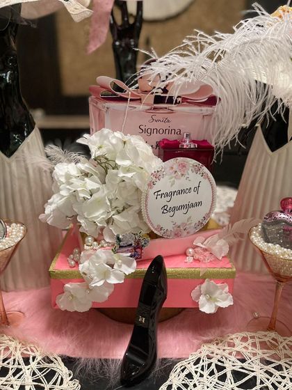 A close-up of a personalized centerpiece from the perfume-themed party. A custom sign, 'Fragrance of Begumjaan', adds a bespoke touch, making the event feel truly unique and special for the guests.