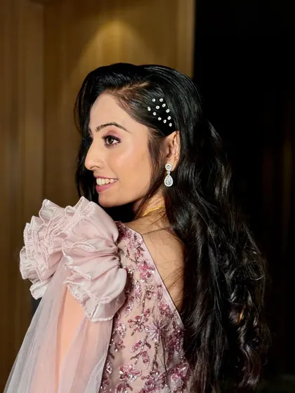 A side profile showcasing the elegant hairstyle with pearl accessories and the soft, glowing makeup of the reception bride.