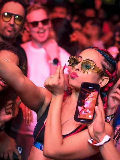 A partygoer taking a selfie in the middle of the crowd. It's a memorable experience.