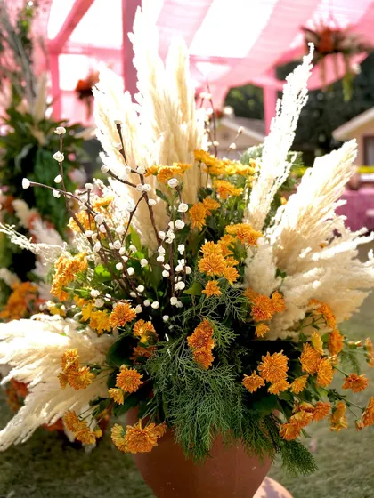 A vibrant floral arrangement with yellow chrysanthemums and fluffy pampas grass, ideal for adding a touch of sunshine to any event.