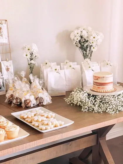 For a rustic yet minimalist bridal shower, I styled this dessert table with simple white flowers, a naked cake, and neatly arranged treats. The focus is on clean presentation and natural elements for a timeless look.