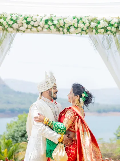 An embrace between the bride and groom under their wedding mandap, with a beautiful lake view.