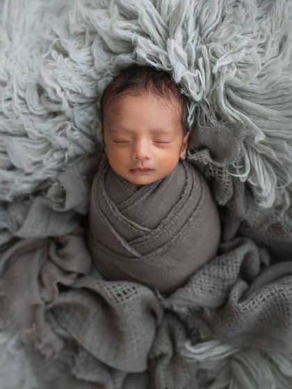 This is a solo portrait of one of the twins, wrapped in a simple grey swaddle. Getting these individual shots is just as important as capturing the pair together.