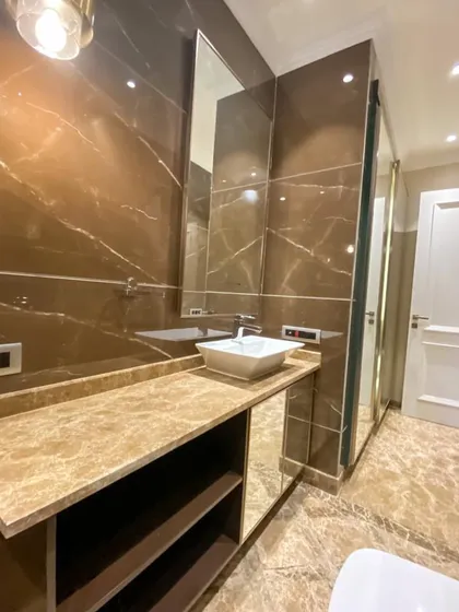 This bathroom at C-926 features a beautiful vanity with a mirrored wardrobe, all set against rich brown Italian marble walls. The design maximizes both style and storage.