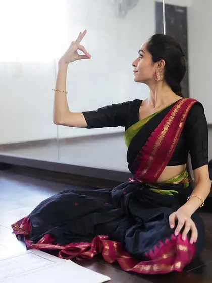 Demonstrating a mudra while seated, with my notes nearby. I combine traditional teaching with structured lesson plans to provide a comprehensive learning experience.