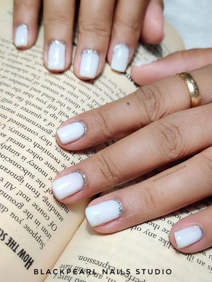 A soft and dreamy look with milky white nails and a delicate silver glitter reverse French. It's a subtle and elegant way to add a touch of sparkle.