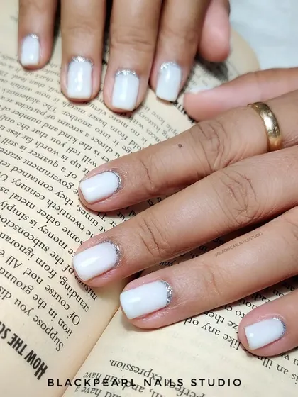 A soft and dreamy look with milky white nails and a delicate silver glitter reverse French. It's a subtle and elegant way to add a touch of sparkle.