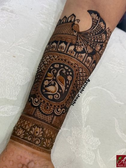 An Indian designer mehendi for a 'varshitap tapasvi', with intricate peacock and swan motifs covering the arm.