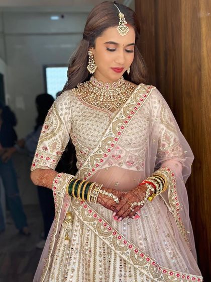 The bride looks poised and elegant in her complete look. The makeup is designed to enhance her features and give her a glamorous glow.