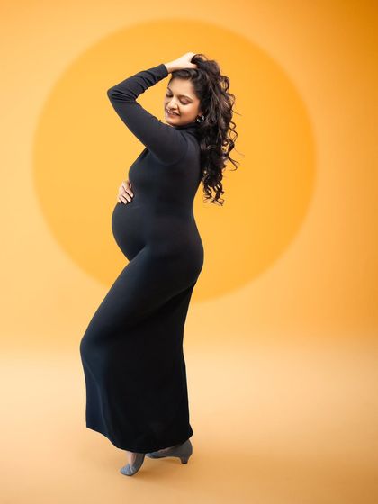 She walks with grace, she carries life, she shines like the sun. This bold and elegant portrait in a black dress against a golden glow is truly timeless.