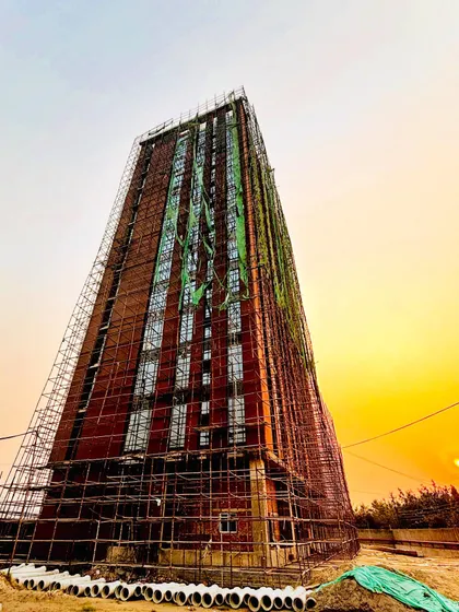 A site visit captures a residential tower during construction, with its exposed brick facade illuminated by the setting sun. We find poetry in the process, where raw materials and structural form come together to create a building that breathes.