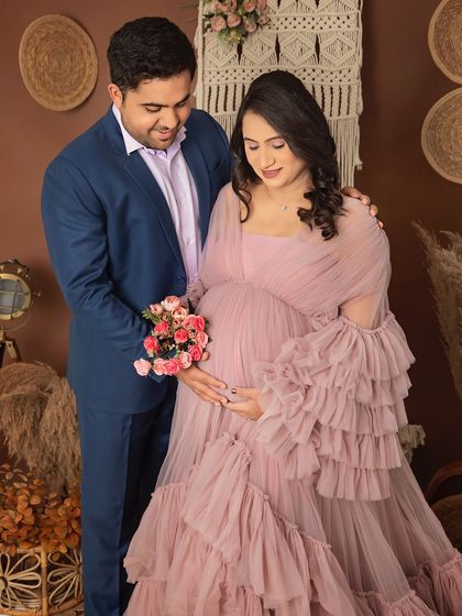 A beautiful moment between an expecting couple. The soft pink gown and the bouquet of flowers add a touch of romance to this maternity portrait in our boho setup.