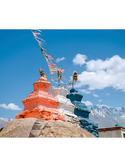 Colorful stupas at Karsha Monastery, with prayer flags fluttering against the backdrop of snow-covered Himalayan peaks.
