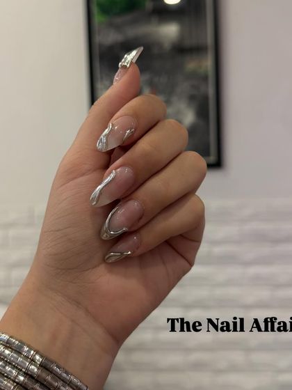 A modern and edgy design featuring abstract, three-dimensional silver chrome swirls on clear almond-shaped extensions.