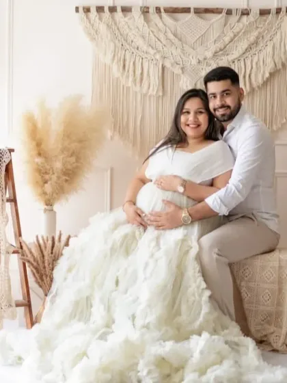 A happy couple sharing a moment in our boho-chic studio setup. This popular theme uses natural textures like macrame and pampas grass to create a warm, stylish, and intimate atmosphere for your maternity photoshoot.