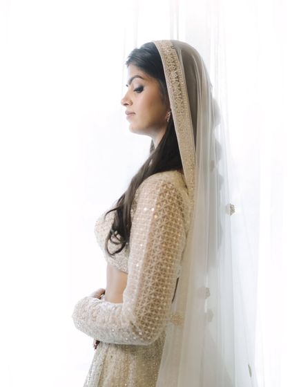 A serene, side-profile portrait of the bride against a bright window. The soft light and her peaceful expression create an ethereal and beautiful shot.