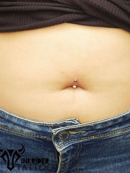 A close-up view of a clean belly button piercing. Notice the placement and the simple, high-quality jewelry used.