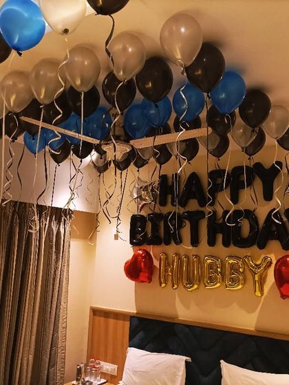 A simple and sweet birthday surprise for a husband. Black, blue, and silver balloons on the ceiling with "Happy Birthday Hubby" foil letters.
