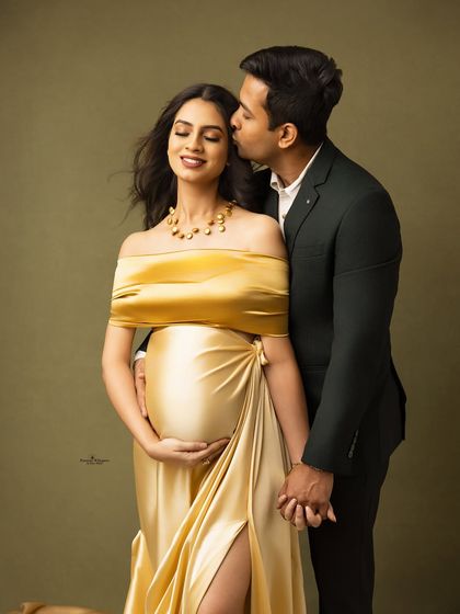A romantic kiss on the cheek captures the love between this expecting couple. The golden gown and classic suit create a timeless and glamorous look.