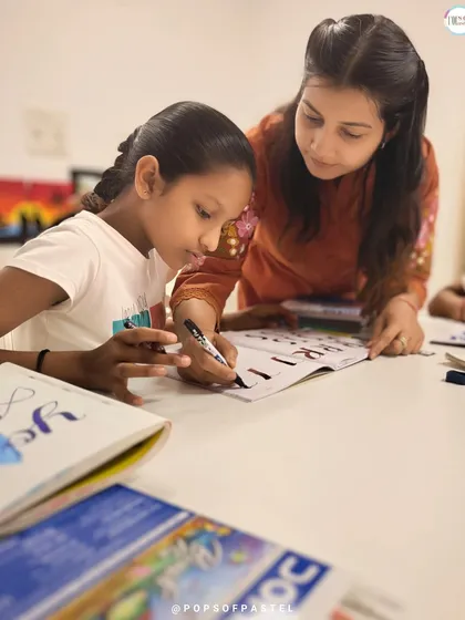 We believe in hands-on guidance. Here, one of our instructors helps a young student perfect her strokes during a brush lettering workshop, ensuring everyone learns and grows.