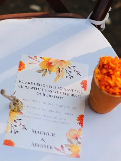It's the little things that make a wedding feel personal. For this ceremony, each guest's seat had a small bell to ring when the bride entered, a cone of fresh marigold petals for the pheras, and a beautiful custom card explaining the traditions.