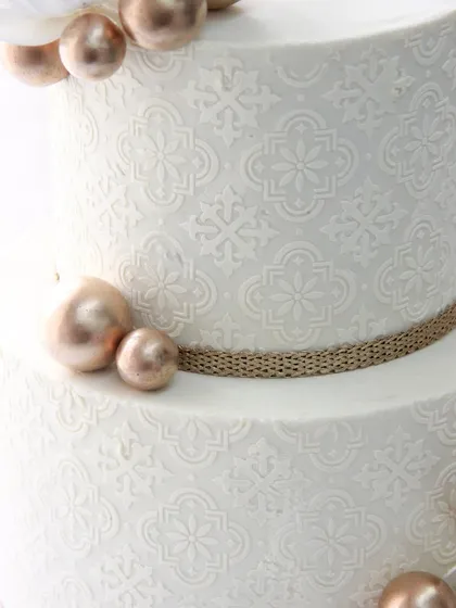 A close-up of the intricate stencil work on the wedding cake, which adds a beautiful texture and depth to the design.