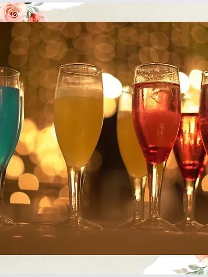 A selection of colourful cocktails and mocktails lined up on the bar, glowing in the ambient light of an evening celebration.