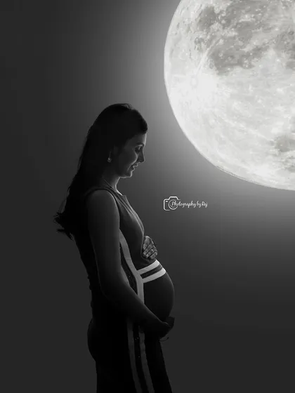 A creative silhouette of a mother-to-be against a full moon backdrop, creating a serene and artistic image.