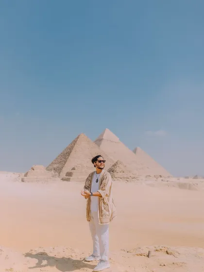 A portrait shot against the clear blue sky and the pyramids. The composition uses negative space to draw attention to both me and the iconic background, creating a clean and powerful travel photo.