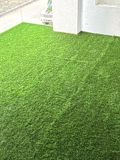 This close-up shows how neatly the artificial grass fits into the corner of a balcony. My precise installation ensures there are no gaps, creating a tidy and complete look for your outdoor space.