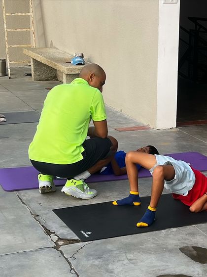 A coach helps a junior player with a glute bridge exercise. Even our youngest athletes learn the importance of proper activation.
