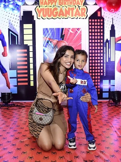 A guest poses with the birthday boy in his Spider-Man suit against the backdrop I designed. The custom spider-web floor decal adds another layer to the immersive theme.