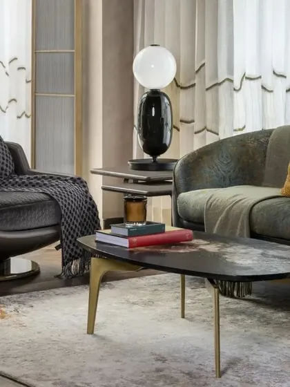 A closer look at the seating arrangement, featuring a modern armchair and custom coffee table with brass legs. Every piece of furniture was selected or designed to contribute to the home's overall narrative of sophisticated comfort.