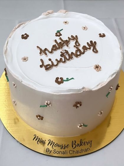 Handcrafted with love. This minimalist cake features delicate, hand-piped brown flowers for a rustic and charming birthday celebration.