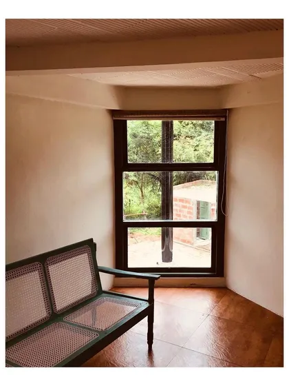A quiet seating nook with a cane bench is perfectly positioned to look out at the surrounding nature. This space was designed for relaxation and to blur the line between the indoor living space and the outdoor environment.