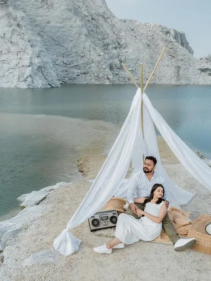 A creatively styled pre-wedding scene where a couple relaxes in a bohemian-style tent by a serene lake. This demonstrates our ability to plan and execute unique, themed engagement photo sessions.