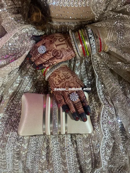 A beautiful shot of the bride's hands with her rings and clutch, showing how the mehendi complements her entire look.