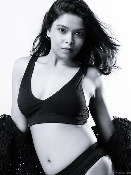 A black and white portrait of a model in a simple black lingerie set, with a soft and natural feel.