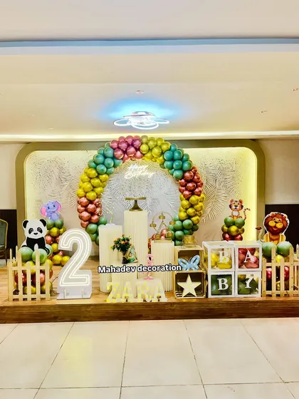 A grand animal theme for a second birthday party on a stage. This decoration includes a large circular balloon arch, various animal foil balloons like a panda and lion, 'BABY' blocks, and a light-up number '2'.