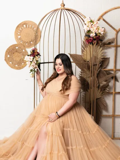 A queen on her throne. This portrait features our bohemian-style set with a large wicker chair and pampas grass, perfect for a rustic and chic maternity shoot.