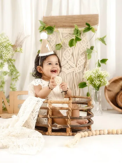Peeking out of a rustic basket, this little one is having a great time at her bohemian first birthday photoshoot.
