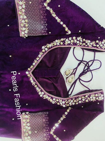 This deep purple velvet blouse has delicate floral embroidery along the neckline and sleeves. The velvet fabric gives it a royal look, and the stitching is strong.