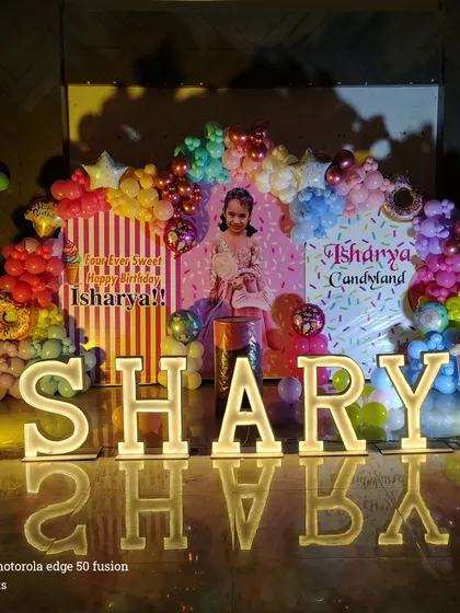 A bright and colorful "Candyland" theme for a 4th birthday, with balloons shaped like donuts and ice cream, and large light-up letters.