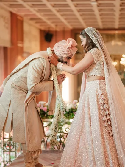 The bride places the Varmala on the groom, who bows respectfully in this traditional and significant wedding ritual.